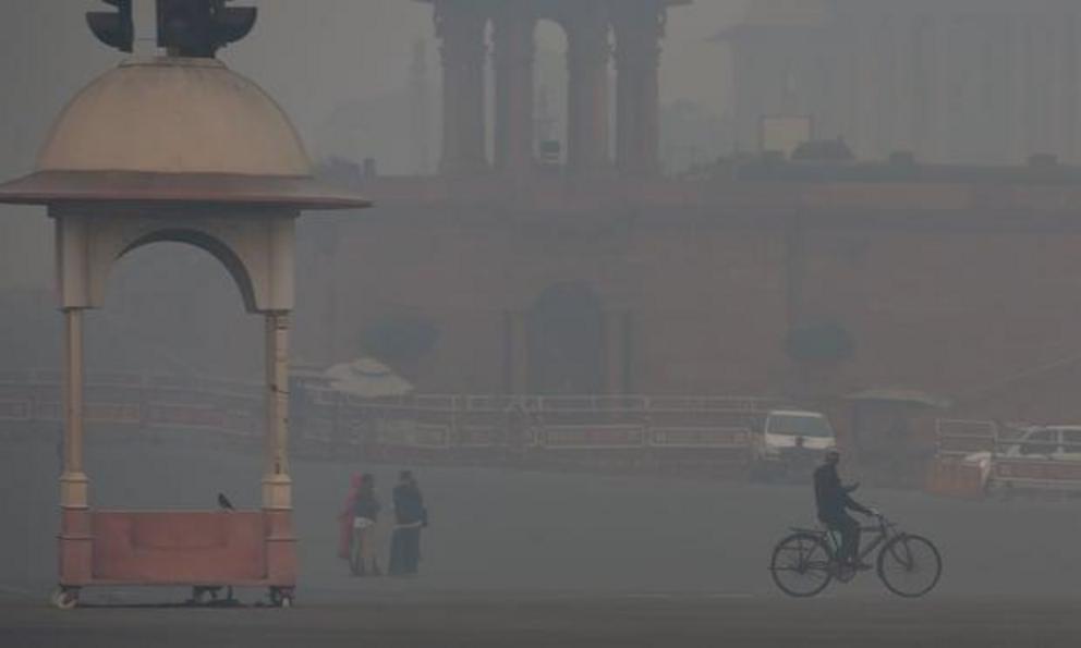 A man cycles past a government building amid heavy smog in Delhi