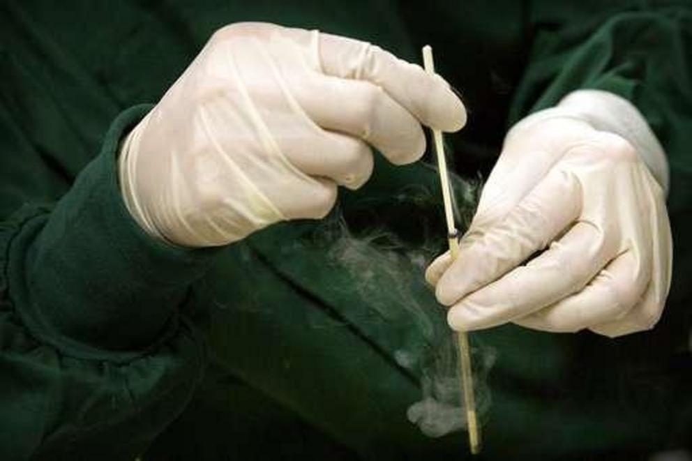 In this Oct. 9, 2018 photo, Zhou Xiaoqin removes the cryostorage sheath from a container for an embryo at a laboratory in Shenzhen in southern China's Guangdong province. Chinese scientist He Jiankui claims he helped make world's first genetically edited 