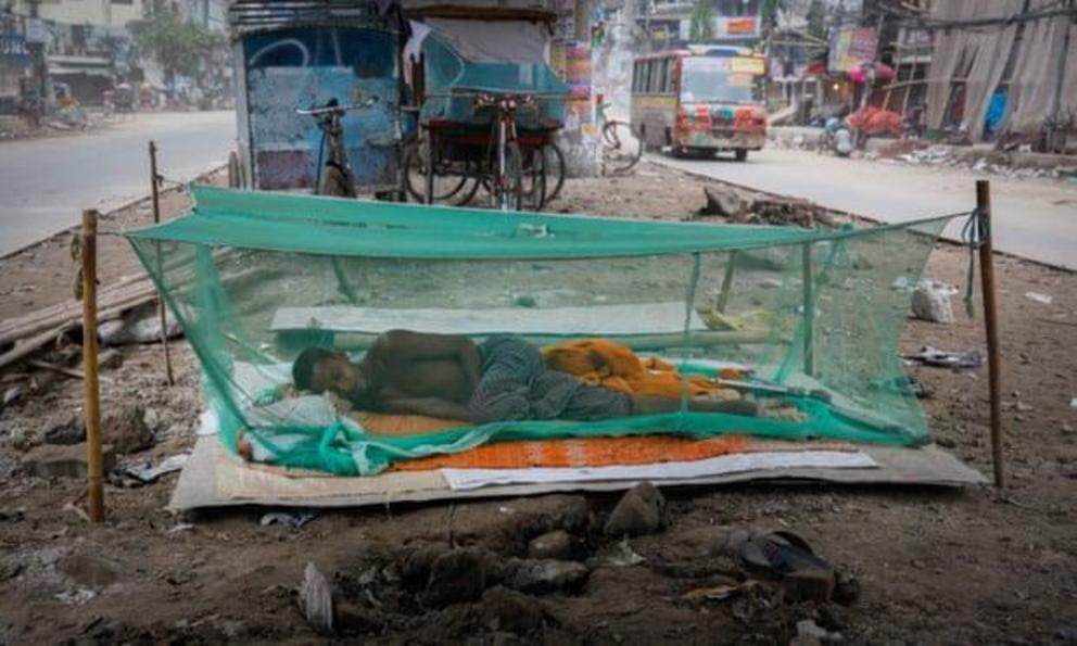 A Bangladeshi worker sleeps under a net to avoid mosquito-borne infections.