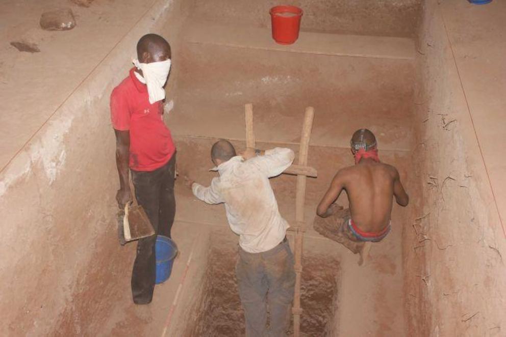 Three men in an archaeological dig site inside the Panga ya Saidi cave 