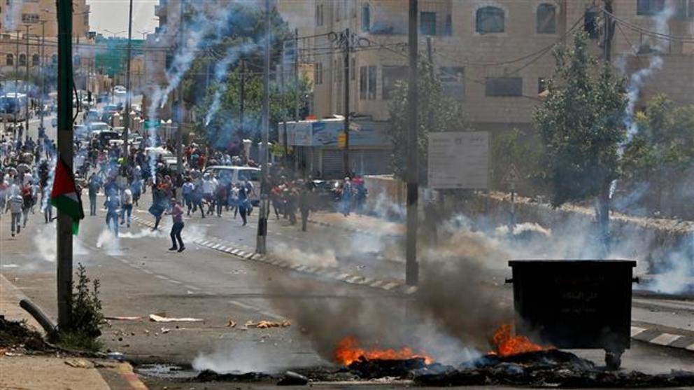 Palestinians throw stones towards Israeli forces during clashes after a protest marking the 70th anniversary of Nakba – also known as Day of the Catastrophe in 1948 – and against the US' relocation of its embassy from Tel Aviv to Jerusalem, at the main en
