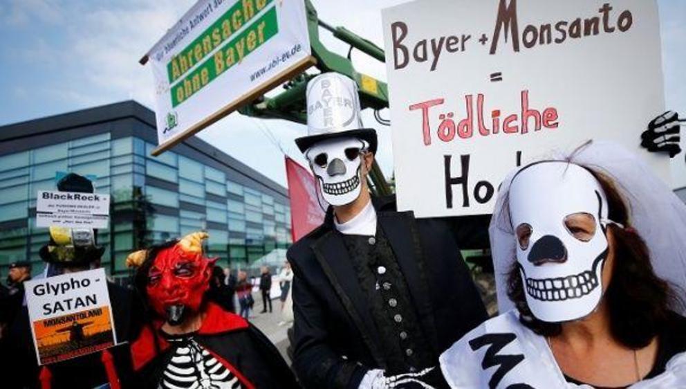 Protesters outside of Bayer's shareholders meeting carry a sign that reads 'Bayer + Monsanto = Deadly' | Photo: Reuters