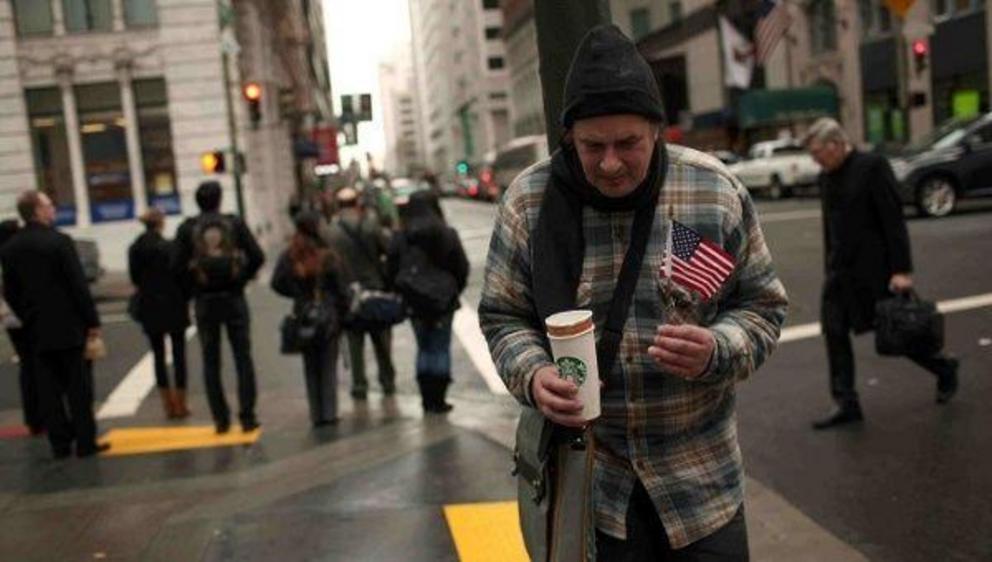 A homeless man begs for money with a U.S. flag and an empty coffee cup in San Francisco, California. | Photo: Reuters