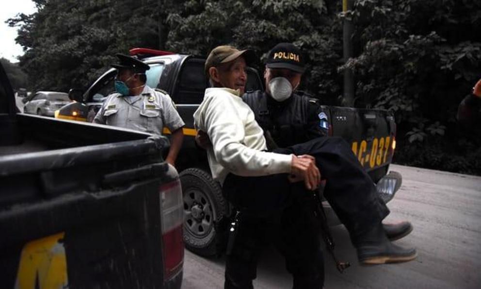 A policeman carries an elderly evacuee in Alotenango, 55 km southwest of Guatemala City 