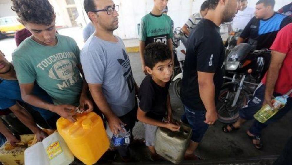 Palestinians wait to fill containers with fuel after Israel stopped the transfer of fuel and cooking gas into Gaza | Photo: Reuters