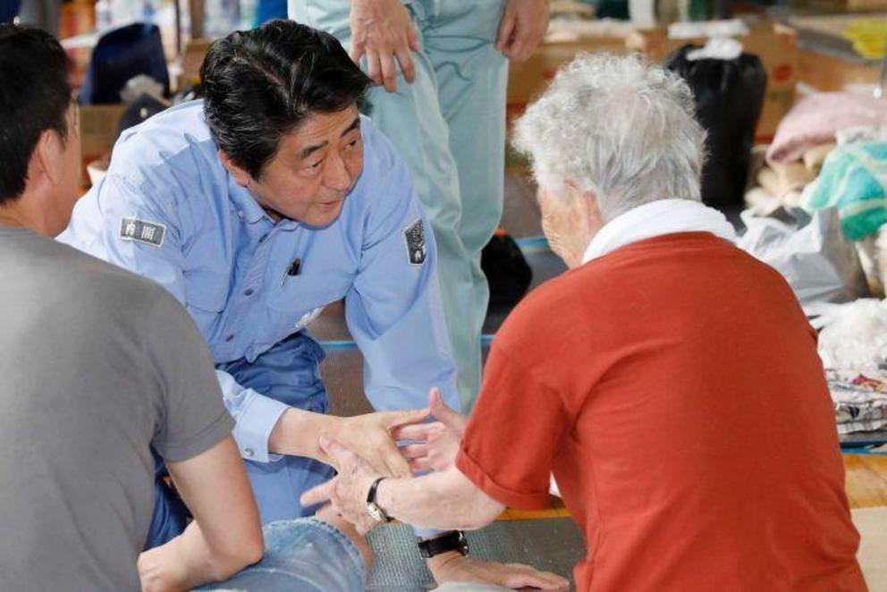 Mr Abe listens to an evacuee during his visit to an evacuation centre in Kurashiki.