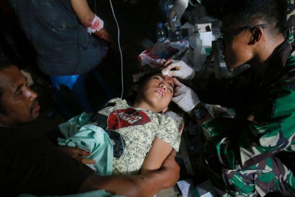 A doctor examines an injured child outside at Army hospital.