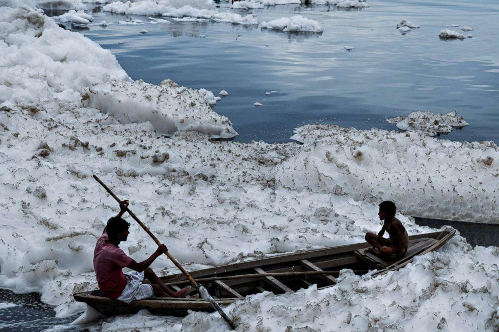 Boys sit in a boat before immersing an idol of Hindu god Lord Ganesh in the polluted Yamuna river on the ninth day of the eleven-day long festival Ganesh Chaturthi in New Delhi on Sept. 21, 2018.