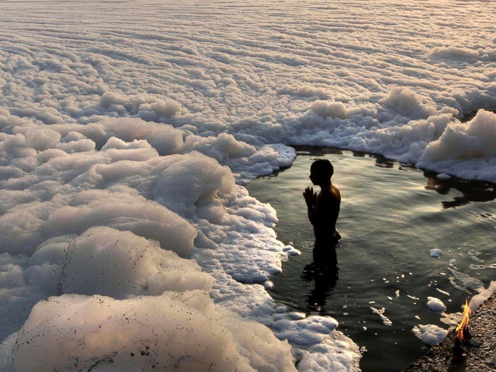 A Hindu devotee offers prayers after a dip in the Yamuna River, surrounded by industrial effluent, during Kartik Purnima festival in New Delhi, Nov. 28, 2012. 