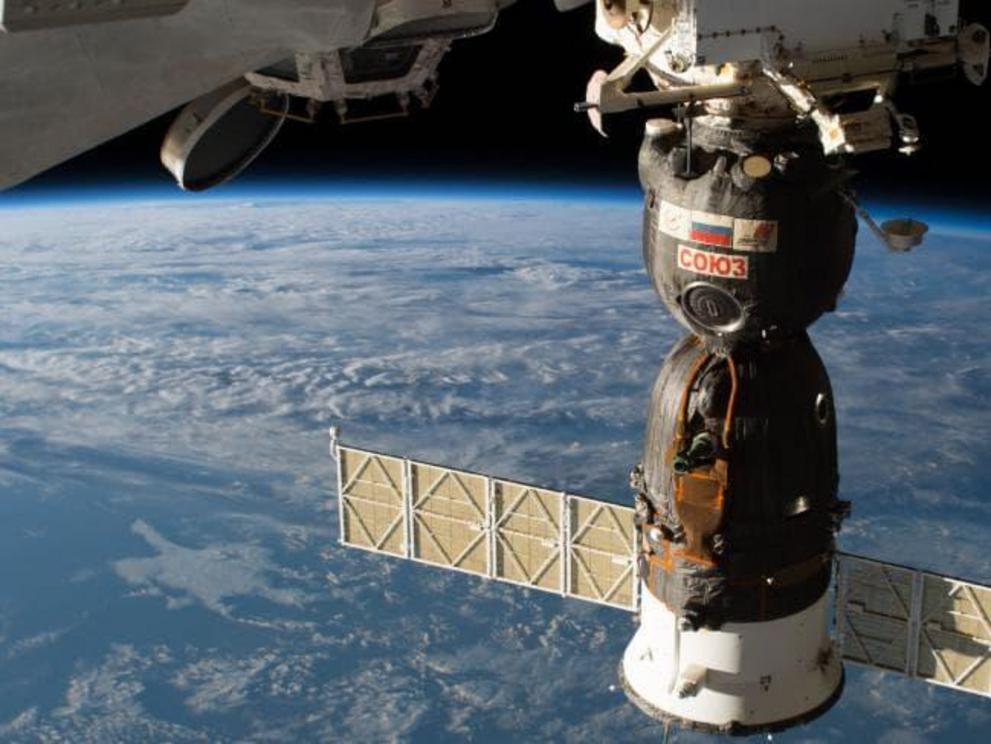A Russian Soyuz orbital module (bottom component) and re-entry vehicle (top circular module) is seen here attached to the International Space Station.