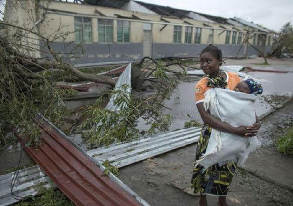 A woman carries her child past debris in Mozambique in the aftermath of Cyclone Idai.