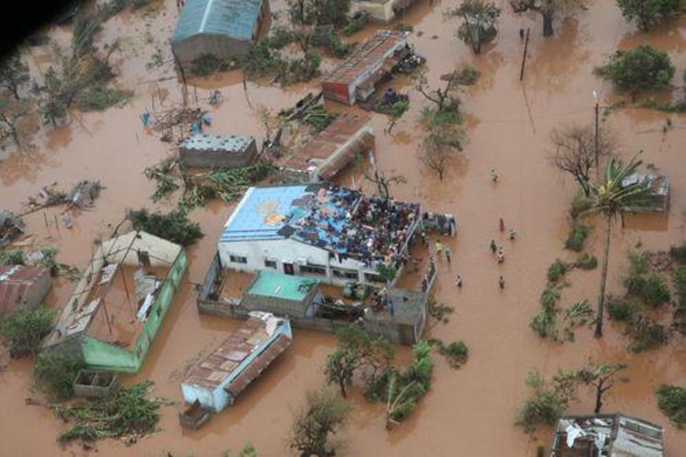 People stand on a rooftop in Mozambique, waiting for rescuers.