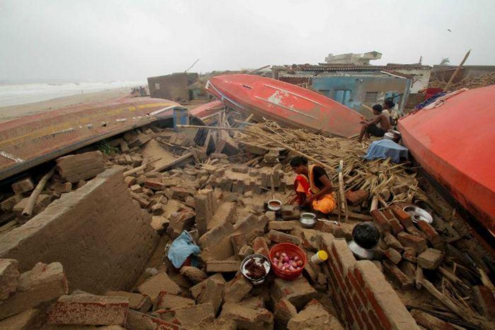 A woman cooks a meal outdoors after her house in the Indian temple town of Puri was damaged by Cyclone Fani.