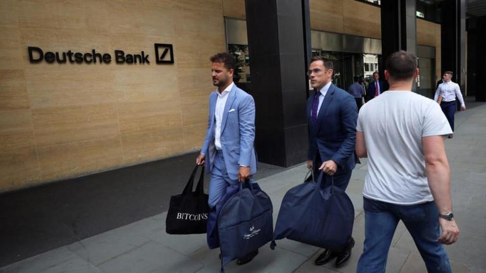 The tailors Alex Riley, left, and Ian Fielding-Calcutt carry suitbags outside the Deutsche Bank building in the City of London © Reuters / Simon Dawson