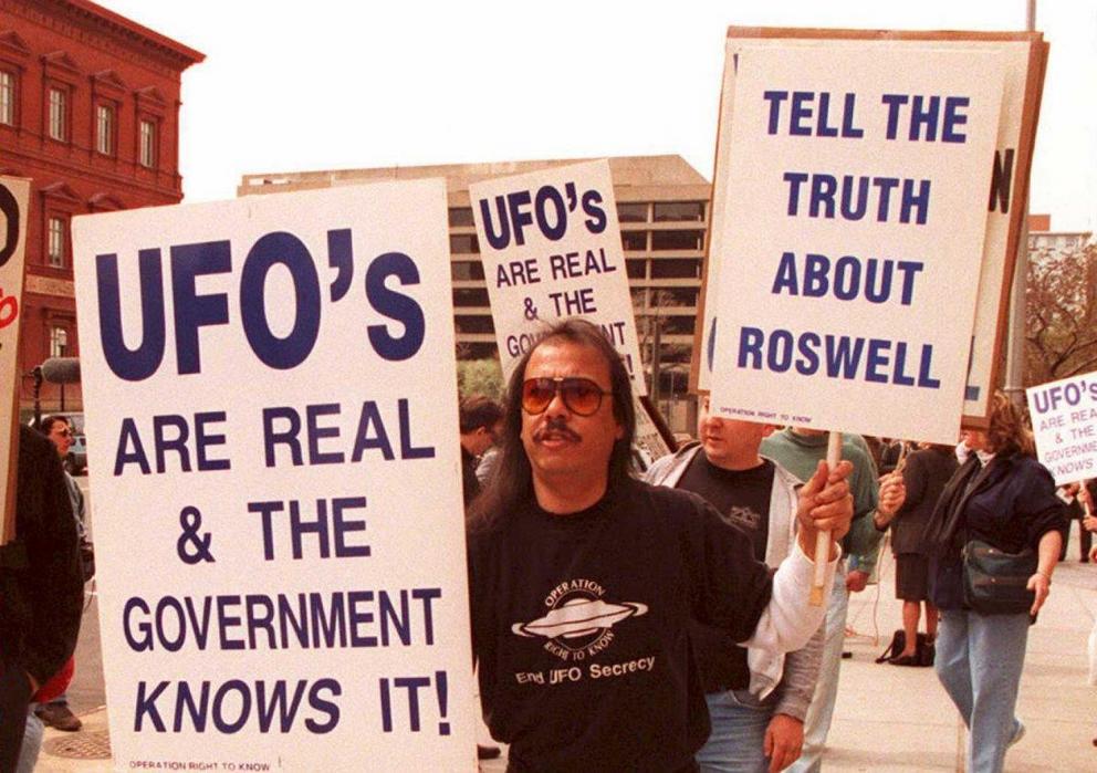 A group of protesters march in front of the General Accounting Office (GAO) in Washington, D.C. on March 29, 1995 to raise awareness about an examination being conducted by the GAO for documents about a weather balloon crash at Roswell, New Mexico in 1947