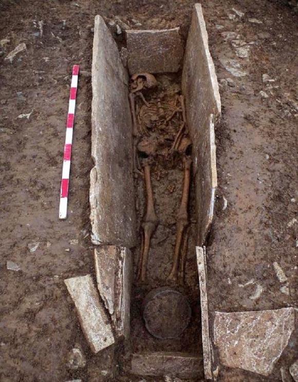 One of the Roman slave skeletons in the stone coffin structure with a pot (at bottom of the shot) unearthed at the burial site in Somerset, England. 
