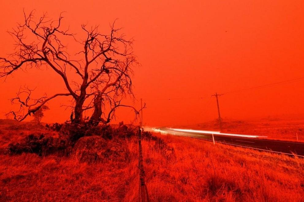 A long-exposure picture shows a car on a road as the sky turns red from the smoke of the Snowy valley bushfire on the outskirts of Cooma, New South Wales.