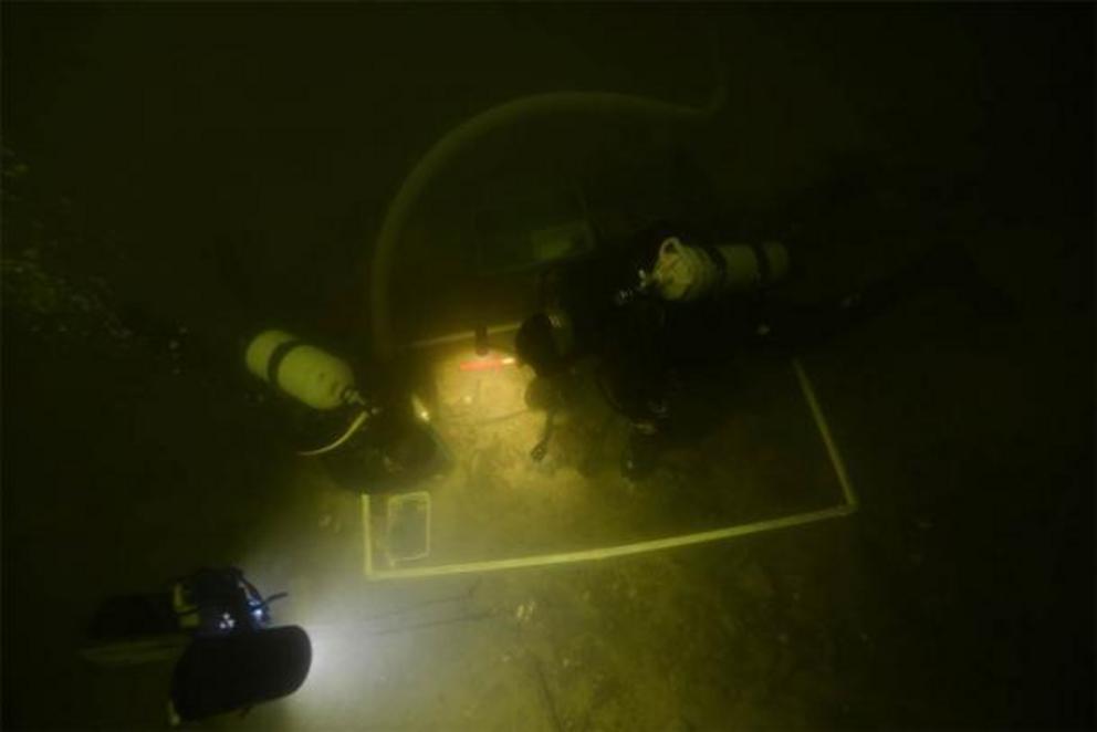 Underwater archaeologists examining the artifacts in Lake Asveja, Lithuania.
