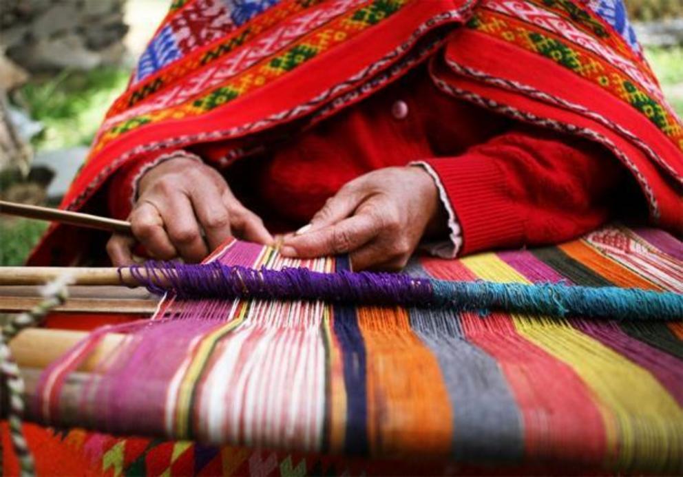 Close up of an indigenous Peruvian woman weaving a traditional textile near Machu Picchu.