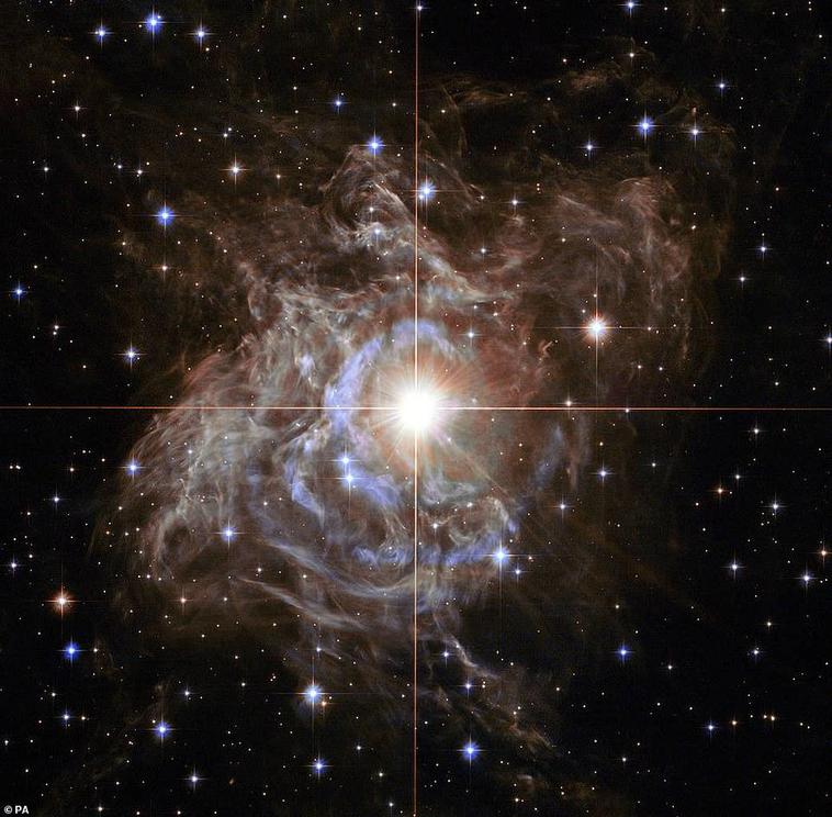 Another example of Hubble's contribution to science is this image of the bright southern hemisphere star RS Puppis, at the center of the image, is swaddled in a gossamer cocoon of reflective dust illuminated by the glittering star. The super star is ten t