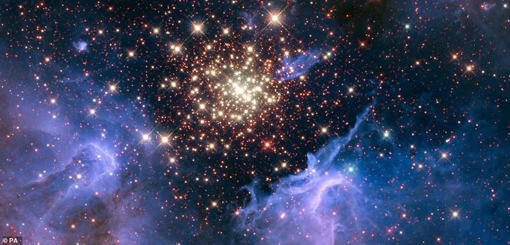 This is an image captured by the Hubble Space Telescope of a young, glittering collection of stars resembling an aerial burst. The cluster is surrounded by clouds of interstellar gas and dust - the raw material for new star formation. The nebula, located 