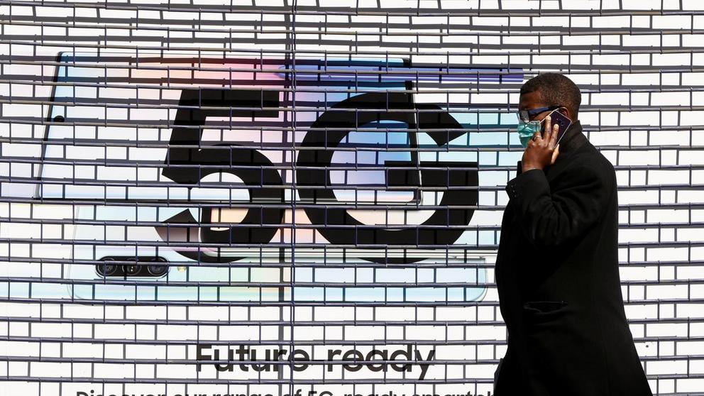 FILE PHOTO: A man wearing a mask walks past a 5G advert as the spread of the coronavirus disease (COVID-19) continues, London, Britain, April 14, 2020 © Reuters / John Sibley 