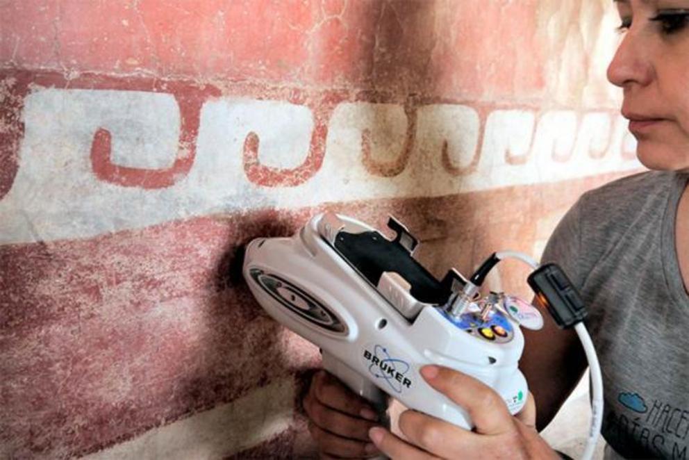 A member of the INAH interdisciplinary team using specialized equipment to identify previously unknown Mesoamerican mural minerals on a wall painting in the Quetzalpapálotl complex.