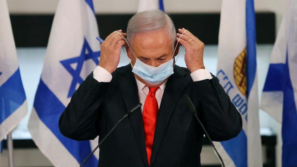 FILE PHOTO: Israeli Prime Minister Benjamin Netanyahu adjusts his mask during a public speech. © Reuters / Alex Kolomoisky 