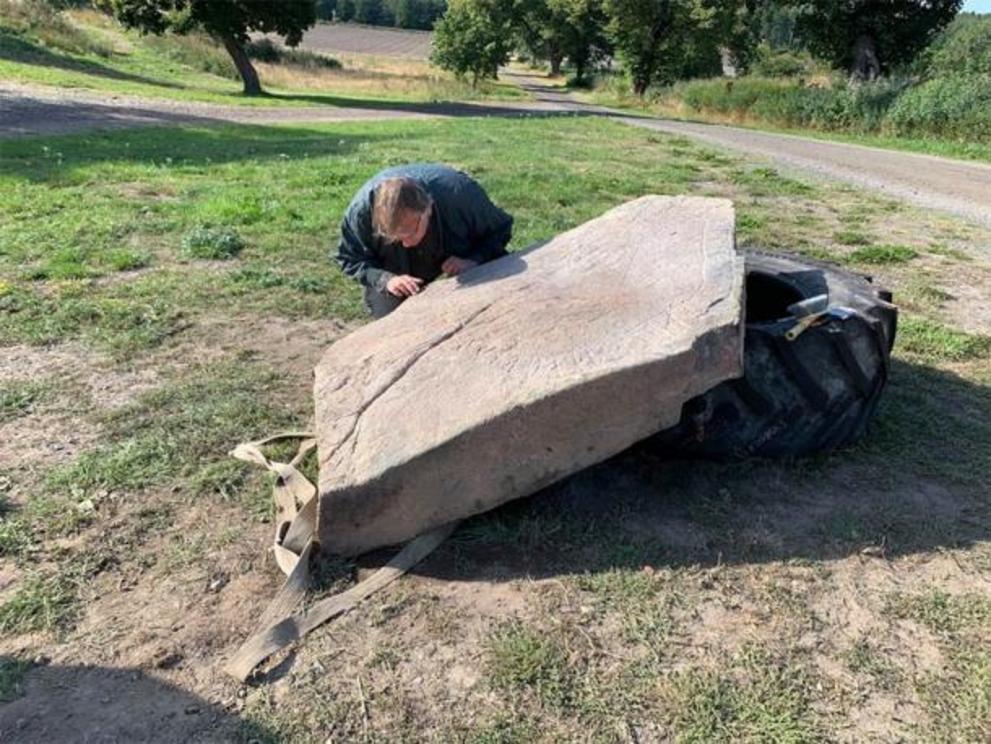 The runologist, Magnus Källström from the Swedish National Heritage Board, studies the newly discovered Viking runestone.