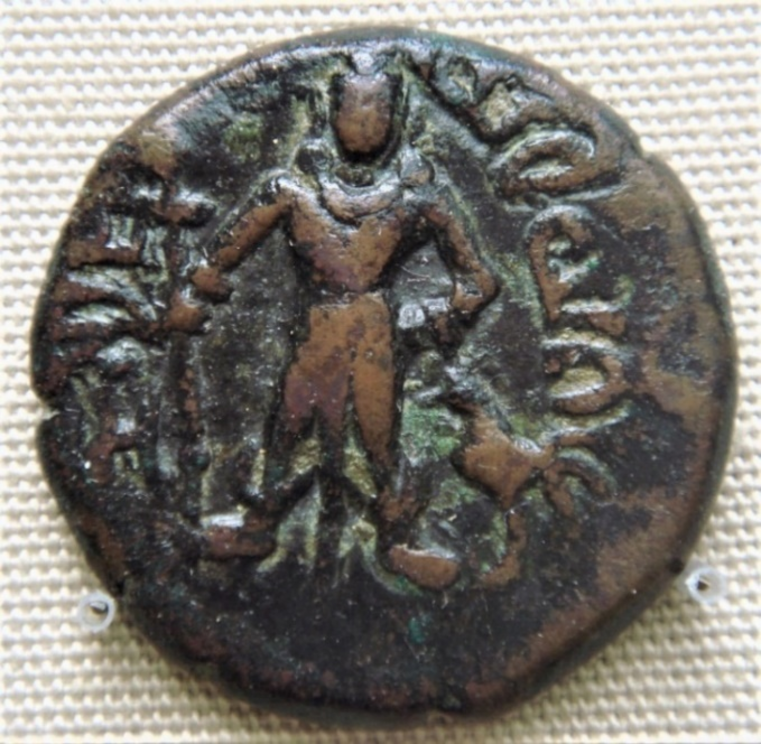 Figure 5: Kartikeya holding a spear / scepter with a cockerel to his left. Coin of the Yaudheyas, British Museum.