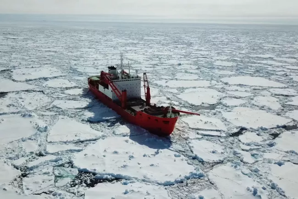 An icebreaker ship navigates through large chunks of Arctic sea ice.