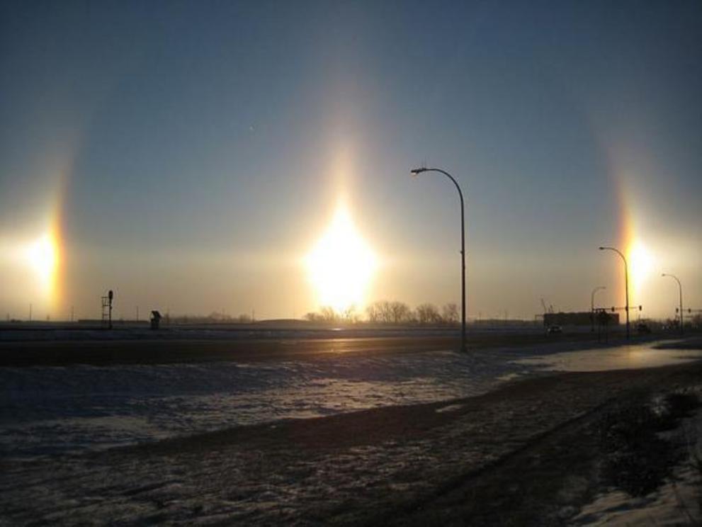Very bright sun dogs in Fargo, North Dakota. Also visible are parts of the 22° halo (the arcs passing through each sundog), a sun pillar (the vertical line) and the parhelic circle (the horizontal line).