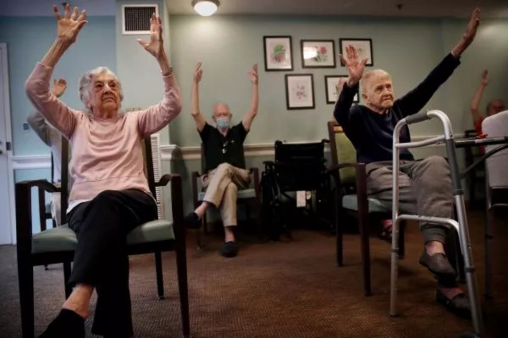 Older people practicing yoga at an assisted living facility to help stay limber; Silicon Valley is working on its own solution to the mobility issues and other problems of older age.