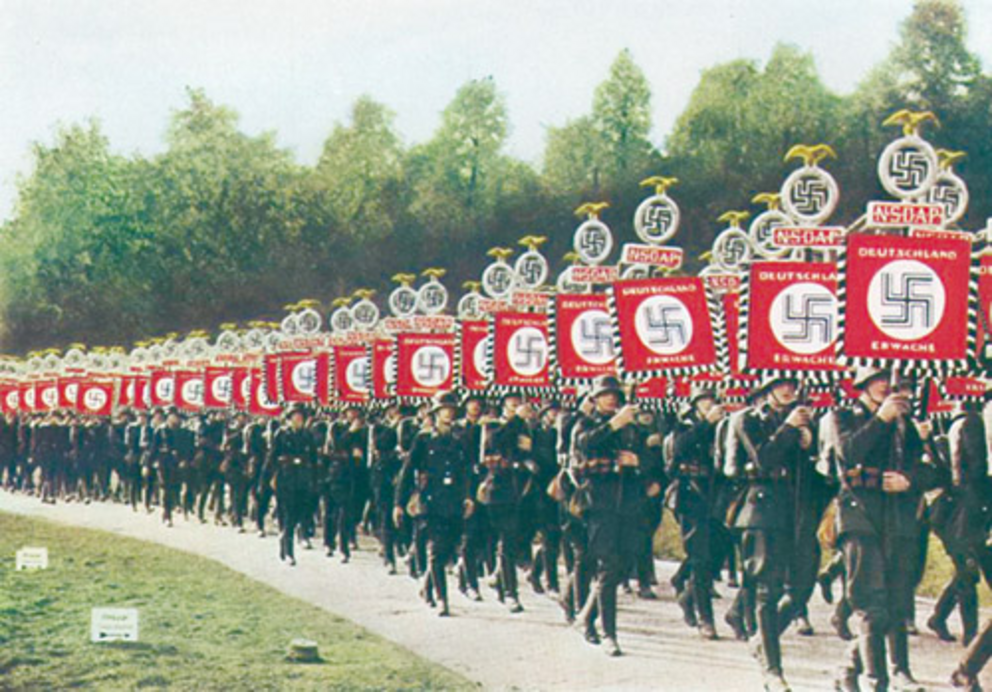 In National Socialist Germany, soldiers carry banners with their borrowed symbol of power: the Swastika.