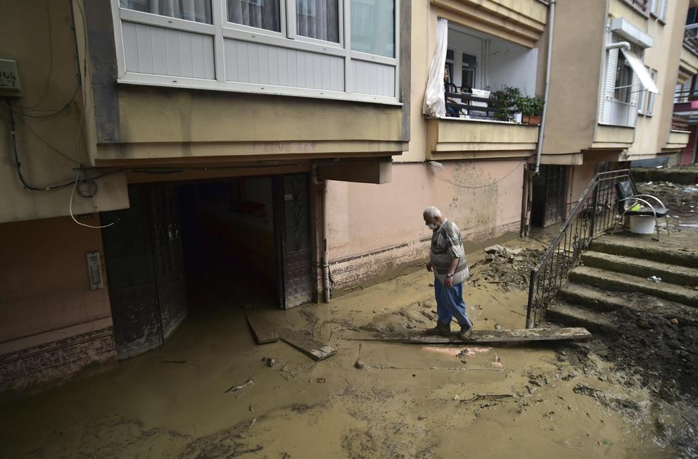 A man tries to reach his mud-filled home after floods and mudslides killed about three dozens of people, in Bozkurt town of Kastamonu province, Turkey, Friday, Aug. 13, 2021.