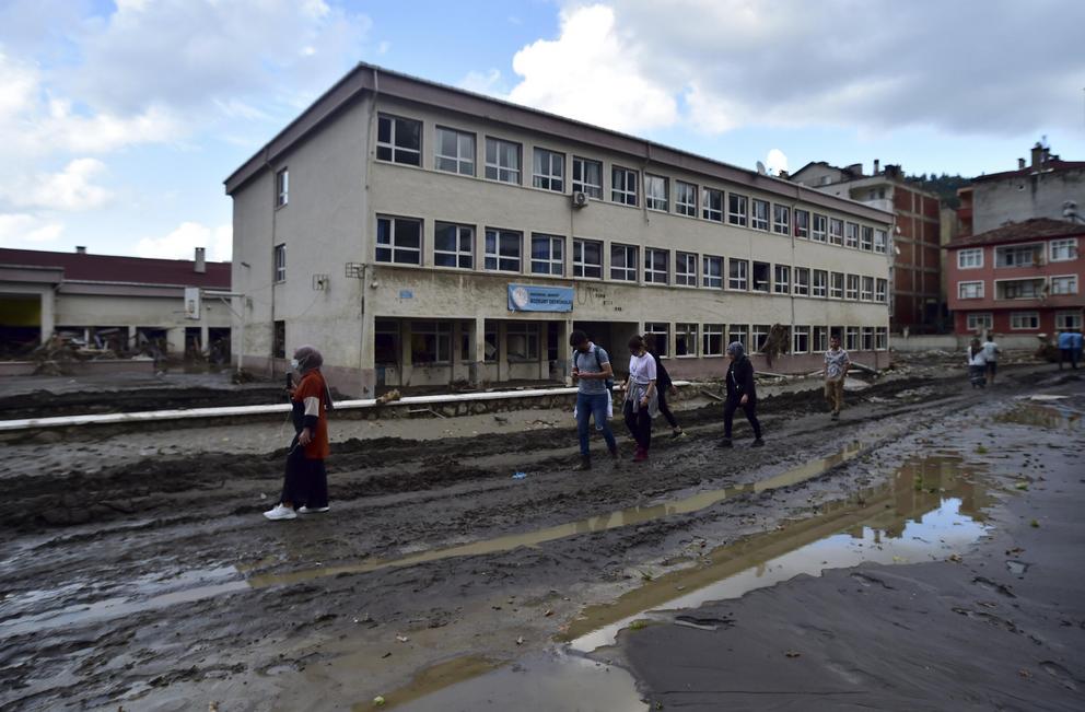 People walk on a mud-covered road after floods and mudslides killed about three dozens of people, in Bozkurt town of Kastamonu province, Turkey, Friday, Aug. 13, 2021.