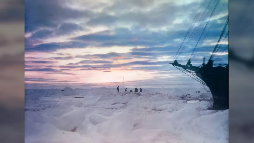 A soft pink light filters over the ice and the crew of the Endurance. The crew attempted to free the ship after it became stuck in the ice, but in mid-February 1915, it was clear that the men would have to winter aboard the vessel. When the spring thaw ca