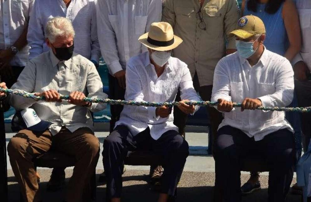 Ecuador's President Guillermo Lasso (C) cuts a rope made of materials collected from coastal cleanups to symbolically inaugurate the expanded Galapagos marine reserve, with former US president Bill Clinton (L) and Colombia's President Ivan Duque.