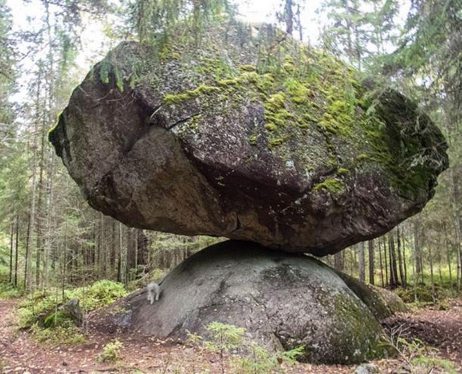 A large precarious boulder called Kummakivi (”Strange stone”), located in Ruokolahti, southeastern FInland. A white miniature schnauzer under it gives an idea of the scale.