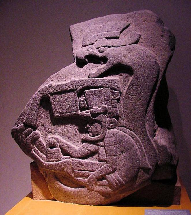 Figure 10: La Venta Stela 19, depicting a deity or priest seated in the coils of a Feathered Serpent. In his right hand he is holding the banduddu, and his left hand is in the varada-mudra posture.