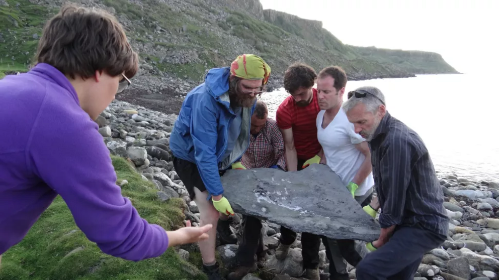 The team lifts the heavy fossil slab on the Isle of Skye, Scotland.