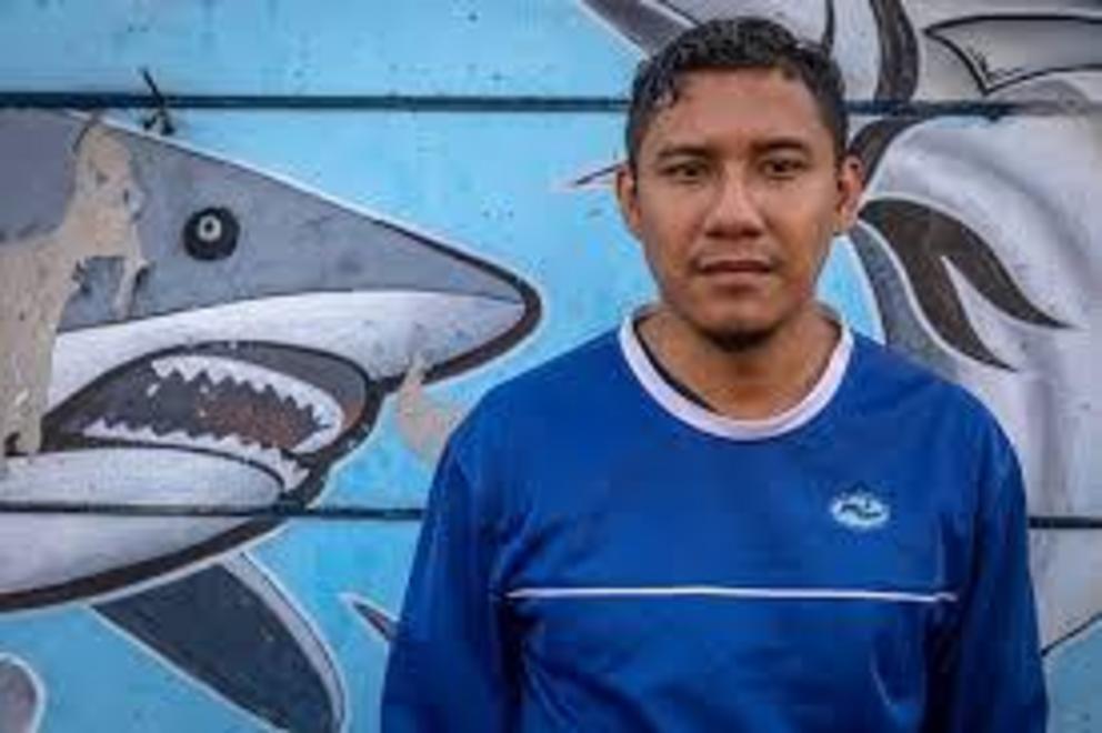 Former deckhand Adhi Tayuh Braka stands in front of a mural at Tanjung Emas Harbor in Semarang, Indonesia, in September. His shirt bears DOF’s logo.