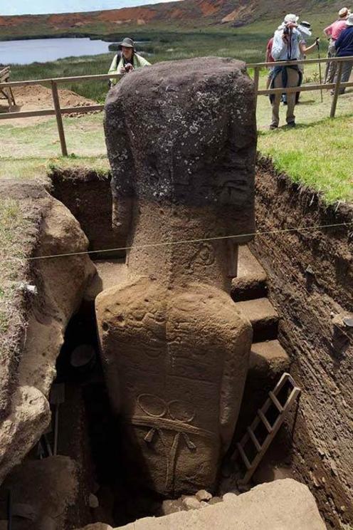 Excavation of one of the moai statues on Easter Island, showing petroglyphs visible on the back of the giant statue.