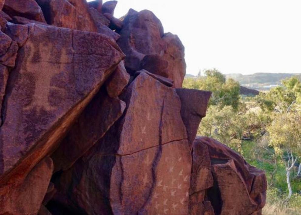 A modern ammonia plant sits side by side with ancient rock art at Murujuga National Park.