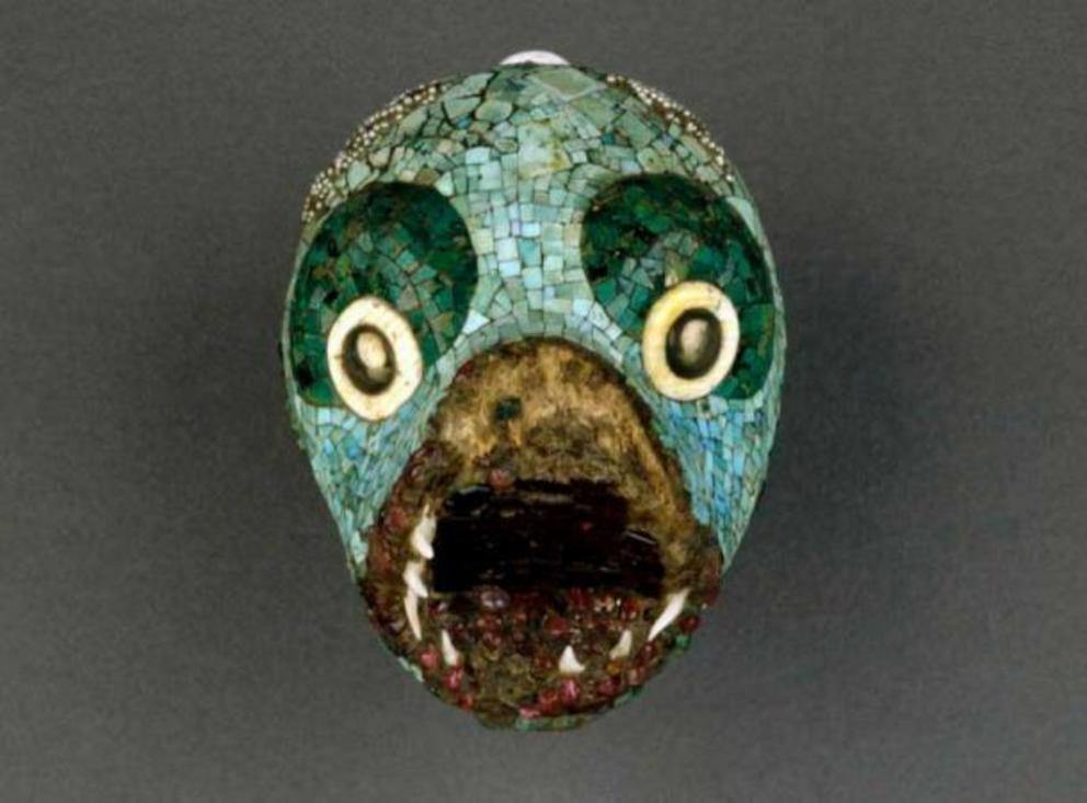 Pendant in the form of an animal head. Made of wood and covered with turquoise and malachite mosaic. The open mouth is encrusted with gemstones and lined with real shark teeth